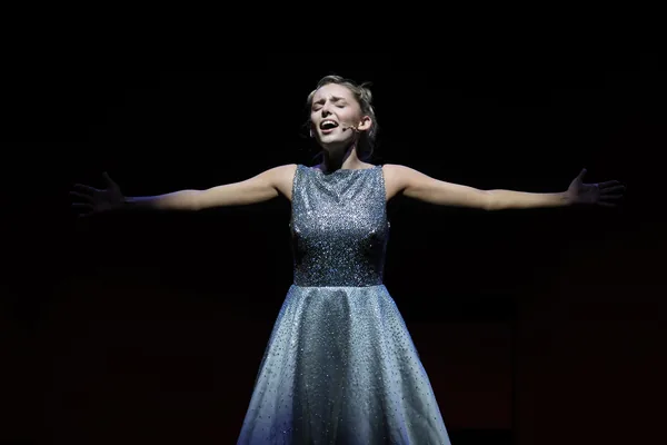 Solo performer singing with arms outstretched