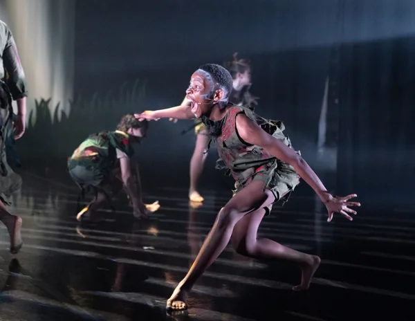 Costumed dancer moving across a reflective stage