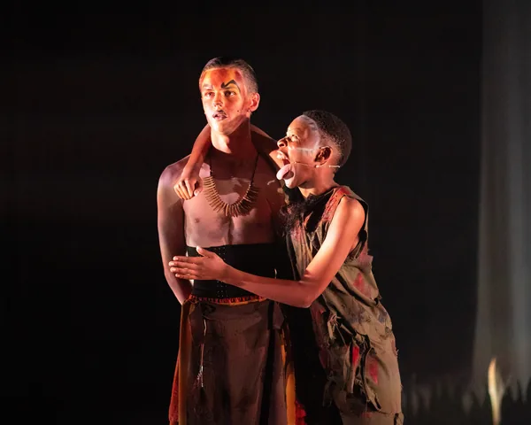 Two costumed performers sharing a dramatic stage moment