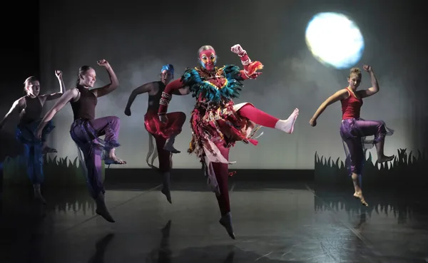Group of performers captured mid-jump on stage