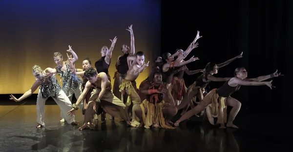 Ensemble of dancers reaching forward together on stage