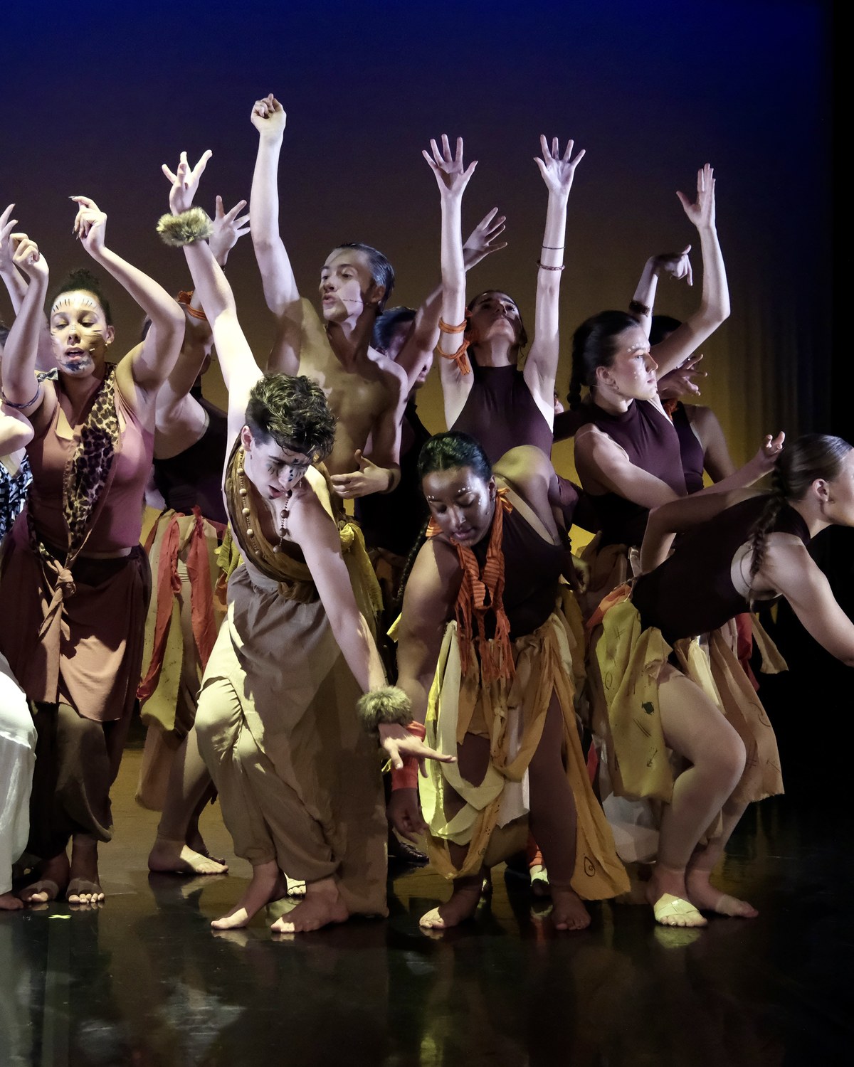 Production ensemble performing together on stage with raised hands