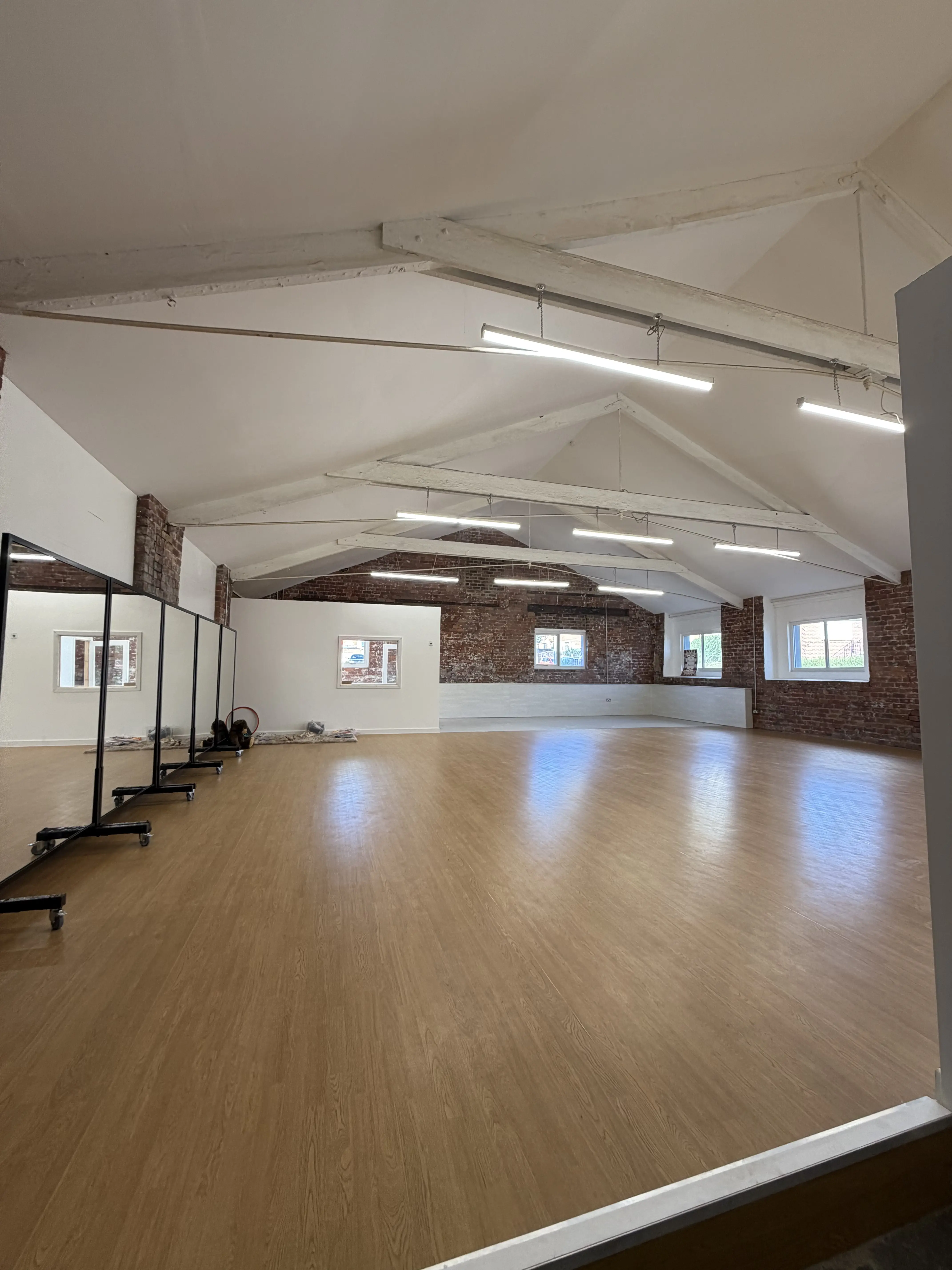 Substantially completed Vibe performing arts studio with a wooden dance floor, mirrors and exposed brickwork